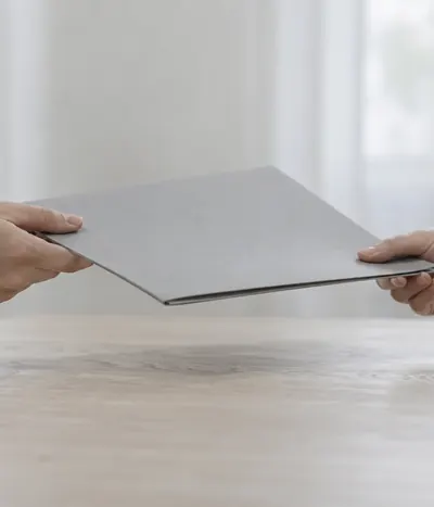 Two hands passing a grey folder across a table